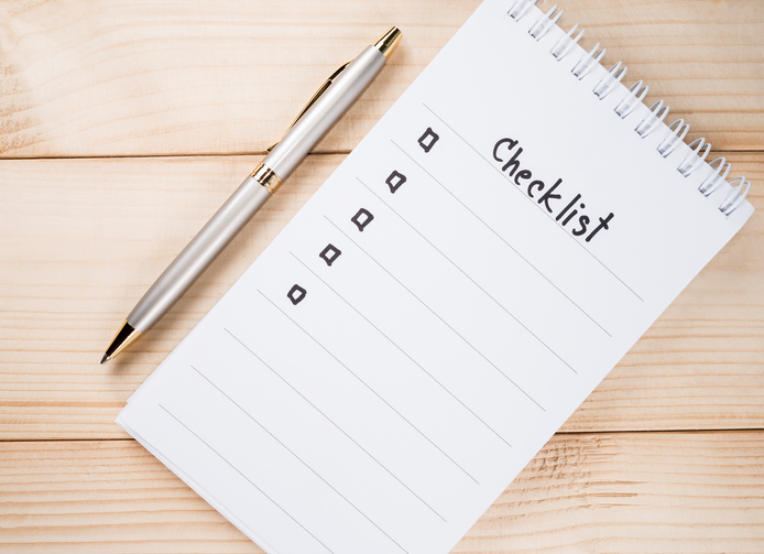 Checklist on notebook page with pen on wood background